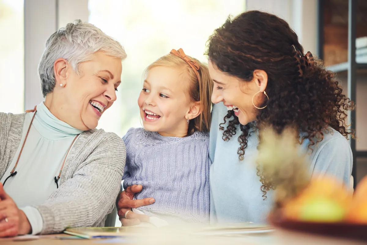 Drei Generationen einer Familie lachen gemeinsam – Großmutter, Tochter und Enkelin